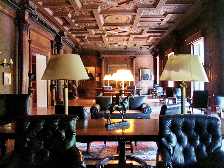 Fig. 2: The Reading Room, which spans eighty feet in length with windows ten feet in height, retains the original ornate molded plaster ceiling and embossed Lincrusta floral wallpaper. The leather-upholstered chairs were commissioned from A. H. Davenport and are original to the room.