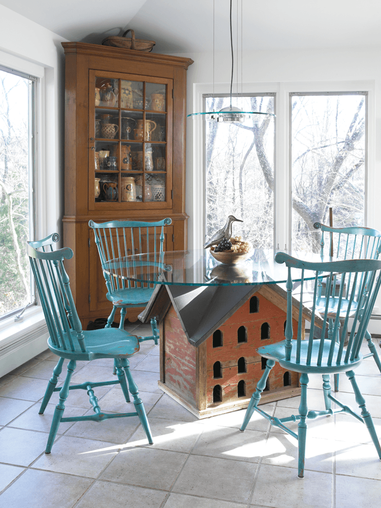 The sun streams into the breakfast room, where the wife converted an early/mid-twentieth-century dove coop into a glass-top table and painted out-of-period Windsor fan-back chairs in a brilliant turquoise. The circa-1820s Pennsylvania cherry corner cabinet holds a collection of French jaspe pottery, mainly acquired from Judy Milne. Other Americana dealers from whom the couple has made purchases include Grace and Elliott Snyder and Howard Szmolko.