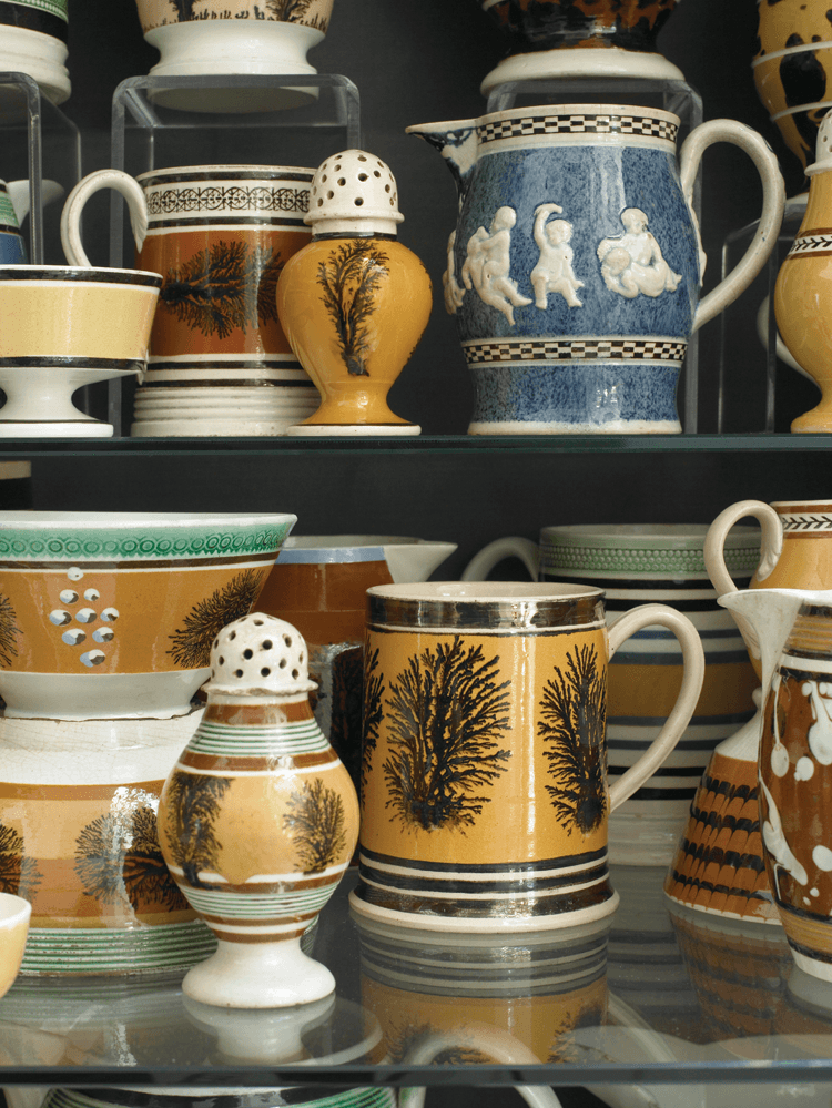 The “dendritic” or seaweed decoration was made from combinations of tobacco juice, manganese and iron oxides, stale urine, and other recipe ingredients to create mocha “tea.” The effect reminded English potters of a type of moss-agate stone referred to as mocha stone because it was exported from a port in the Southern tip of the Saudi Arabian peninsula (now Yemen) called Mukha; hence the origin of the term mochaware. The central truncated mug is quite rare in its use of copper luster bands. The small jug with cobalt blue mottled surface adorned with putti sprigging is also quite unusual.