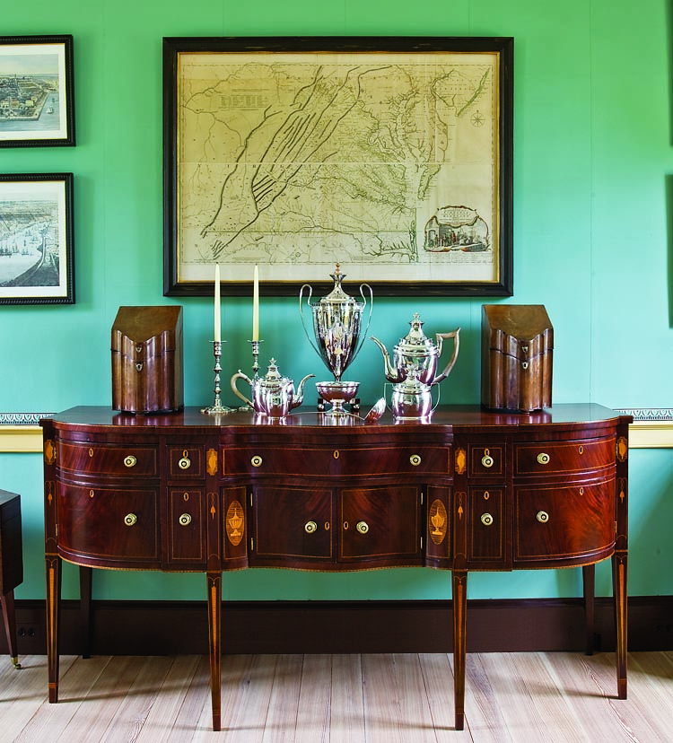 Each leg of the circa-1800 Virginia sideboard, made of mahogany and cherry with boxwood and maple veneers, has stylized inlay of a shell, intertwined guilloche, bellflower, icicle, and cuff, and the doors have a prominent inlaid urn within an oval. The pair of English mahogany knife boxes, with serpentine shaped front, silver shield escutcheons, and an eight-pointed inlaid star inside the inner lid, are believed to have been given by Thomas Jefferson to John Hartwell Cocke II, about 1800. A Map of the Most Inhabited Part of Virginia, drawn by Joshua Frye and Peter Jefferson, was engraved by Robert Sayer and Thomas Jefferys, London, 1775. The silver set was made by W. G. Forbes, New York, 1795–1802, and the hot water urn is English Sheffield plate, circa 1800.