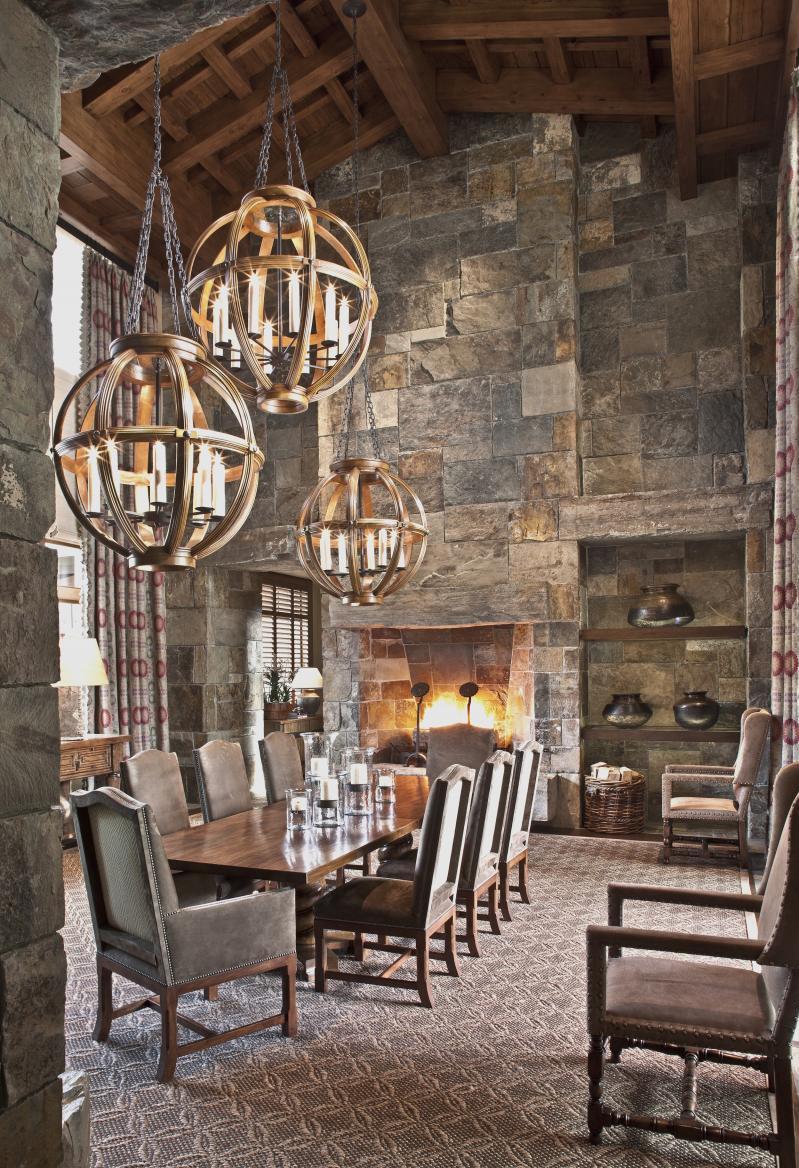 The rustic dining room furniture is situated around a grand fireplace.