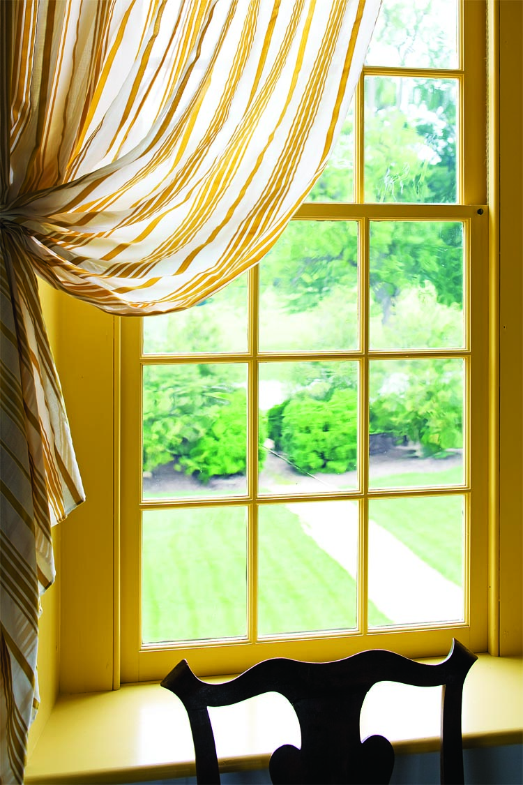 A view to the front of the house is framed by seersucker window curtains of silk and cotton stripe, which have historic precedence.