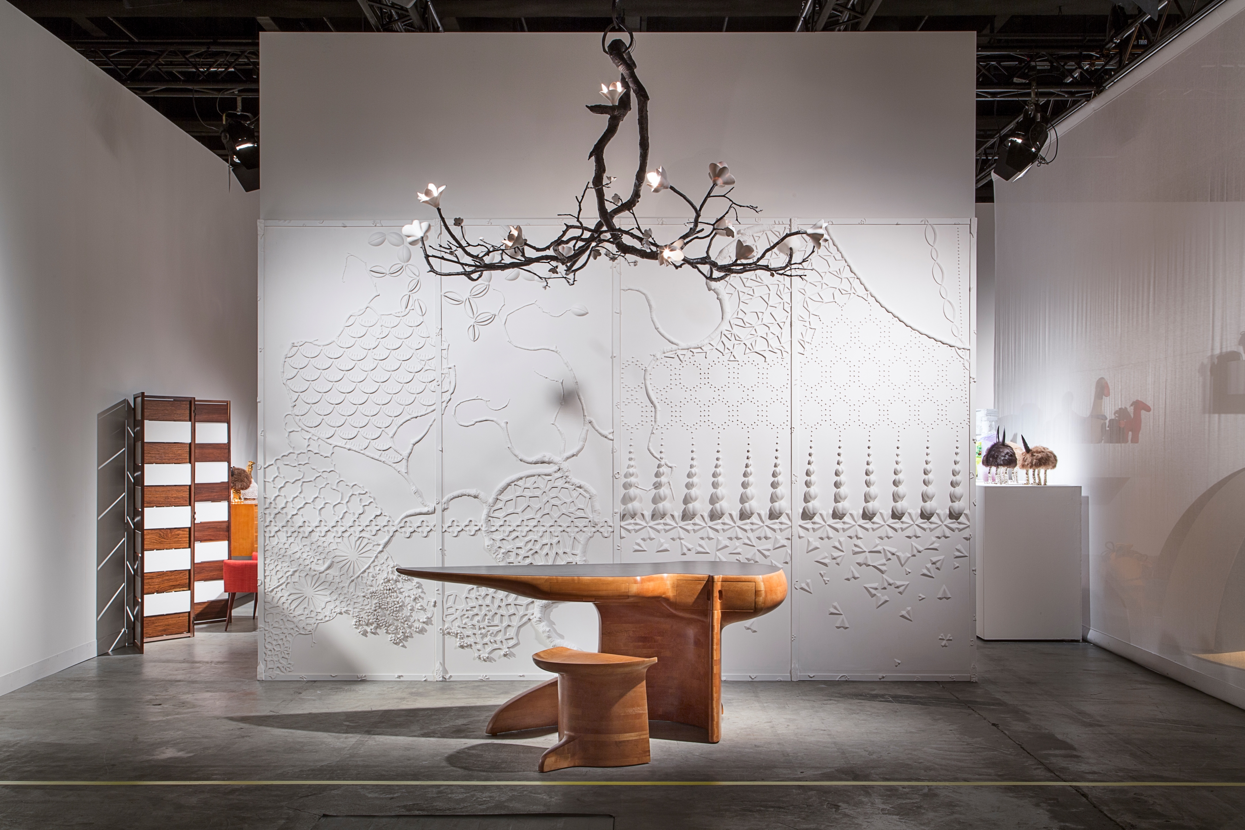 David Wiseman's Radial Branch chandelier above a unique historical desk and stool by Wendell Castle. David Wiseman's unique Collage Chinoiserie paneled wall installation in plaster and porcelain appears in the background. Image courtesy of Joe Kramm/R & Company.