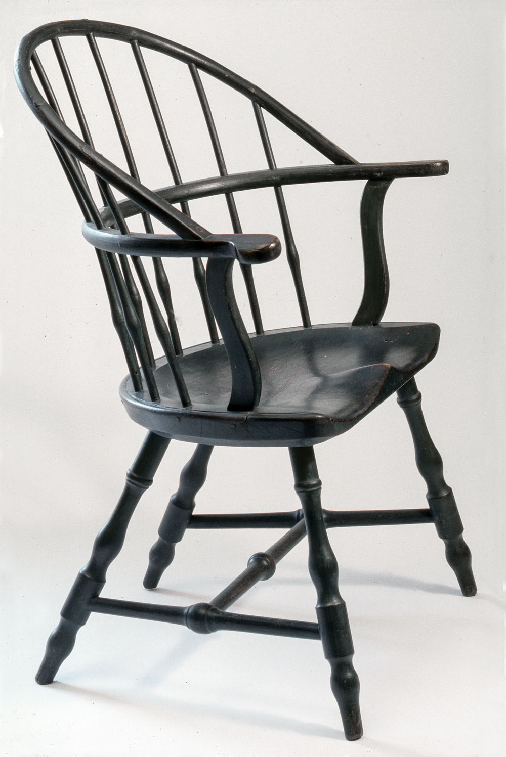 Fig. 9: Sack-back Windsor armchair, probably Providence, ca. 1780–1785. Maple, ash, and oak. H. 37¼, W. 28½, D. 15¾ in. Probably Norman Herreshoff House, Bristol, R.I. A notable feature of this chair is its overbuilt construction that includes a thick bow mounted low and forward and extensive pinning. This prototype Windsor is one of an original pair. It was owned by a direct descendant of Rhode Island merchant John Brown. Its mate bears the incised inscription “I.BROWN” on the top surface of the proper-left arm terminal and is in the collection of the Rhode Island Historical Society, Providence. (RIF1269).
