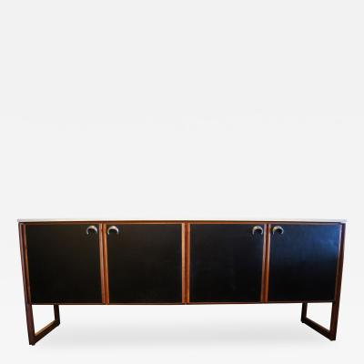 Designed by Jens Risom, this striking walnut sideboard features a travertine top and four leather-panelled doors with large curved aluminium pulls. The interior compartments have four shelves and four drawers, all in high-gloss white paint. C. 1960s. Offered by Machine Age.