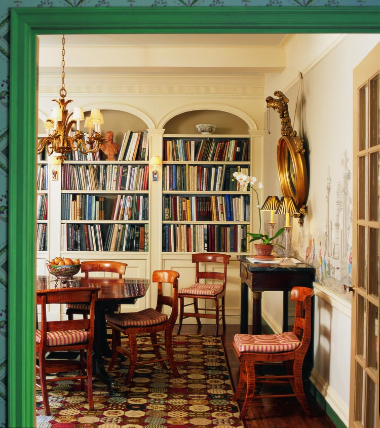 The combination dining room and library features a New York pier table with feet that match a suite Duncan Phyfe made for his daughter. The Classical Boston dining table, “is the most refined of the group, in my mind,” says Nathan. It is surrounded by a set of New York curly maple Klismos chairs. Historic interiors decorator Ralph Harvard designed the bookcases. Photography by Celia Pearson.