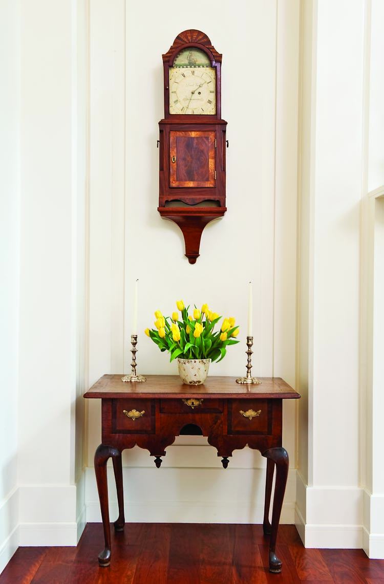 Set off in a corner of the great room is a rare, small, veneered maple Queen Anne dressing table, measuring only 28½ inches wide. This piece was probably made in the Hartford, Conn., area, circa 1740. A nearly identical example is shown in Connecticut Valley Furniture, Kugelman and Lionetti (2005). Above the dressing table is an exceptional mahogany shelf clock signed “David Wood of Newburyport.” The interior door of this circa 1805 Massachusetts clock retains his label “David Wood Watch and Clockmaker Newburyport.” A similar clock is in the Department of State collection, as seen in Treasures of State, Conger and Rollins (1991).