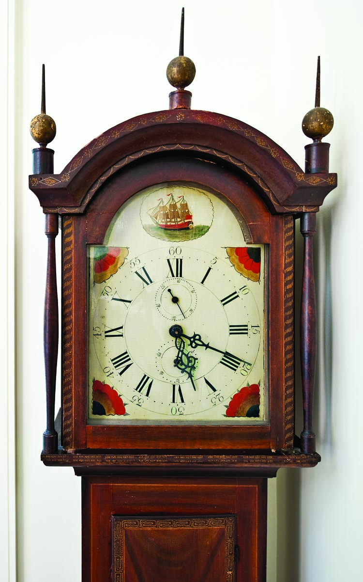 In a corner of the kitchen is a small wooden works clock with a wonderful dry grain-painted surface. The brightly-painted dial is centered by a three-masted ship, and the free-hand decoration simulating inlay on the hood is exceptional. Leaves, diamonds, circles, vines, flowers, and garlands are detailed in white, yellow, orange, red, and black.