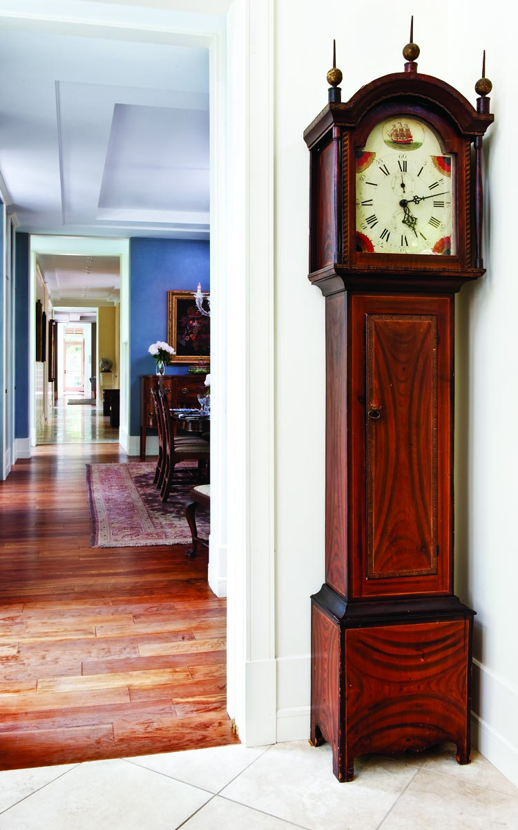The “Greek key” inlay banding on the case door is painted in gold, as are the “brass” finials. This minutely detailed decoration stands in contrast with the broad swaths of grained paint on the case. With a chestnut backboard and old repair labels from two towns in Rhode Island, this clock was probably made there in circa 1815–1820.